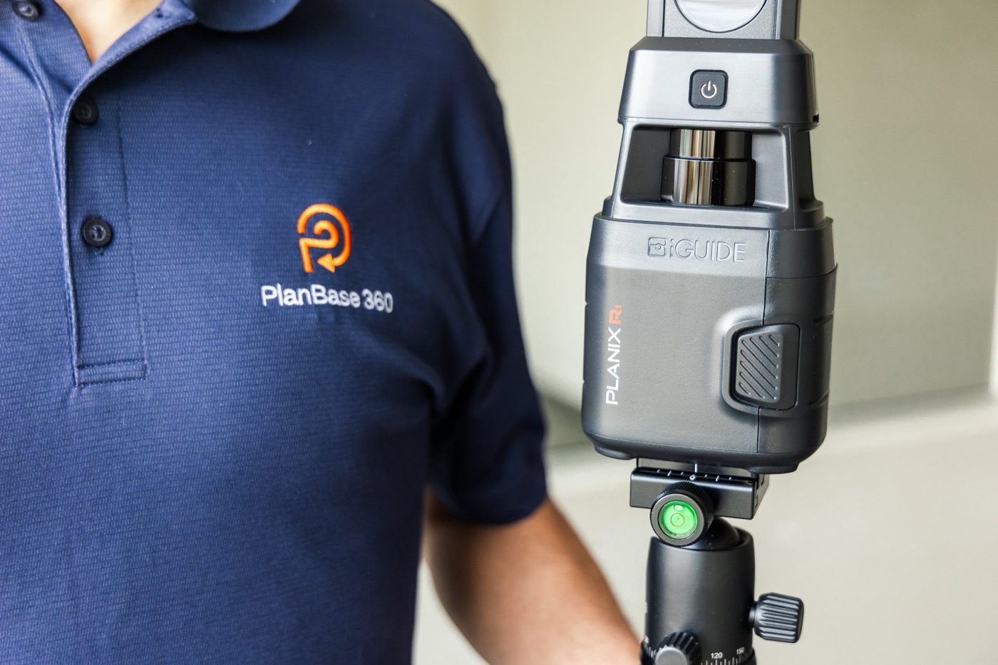 PlanBase 360 operator standing beside a tripod-mounted LiDAR scanner during a commercial survey