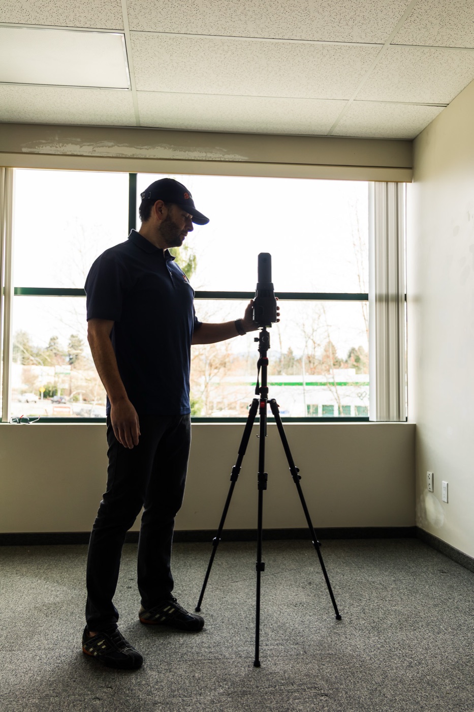 LiDAR scanner capturing an open-plan commercial office floor beside a window wall