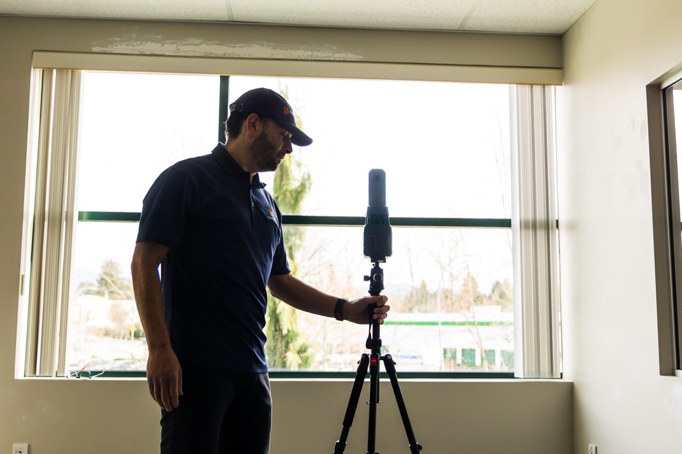 PlanBase 360 operator silhouetted while positioning a LiDAR scanner in a commercial interior