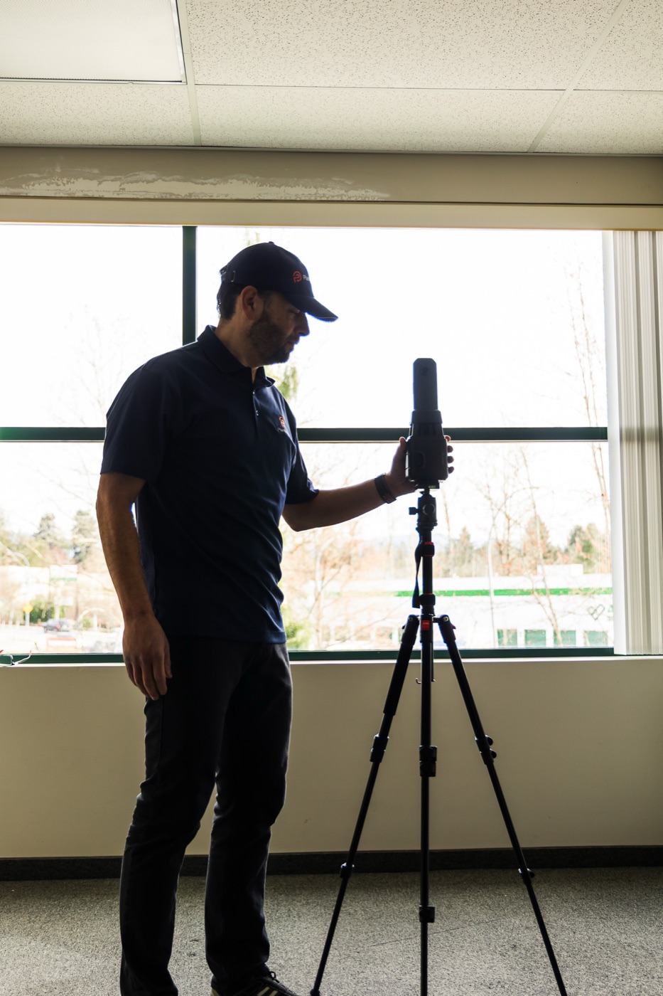PlanBase 360 operator positioning a LiDAR scanner beside a bright window inside a commercial building